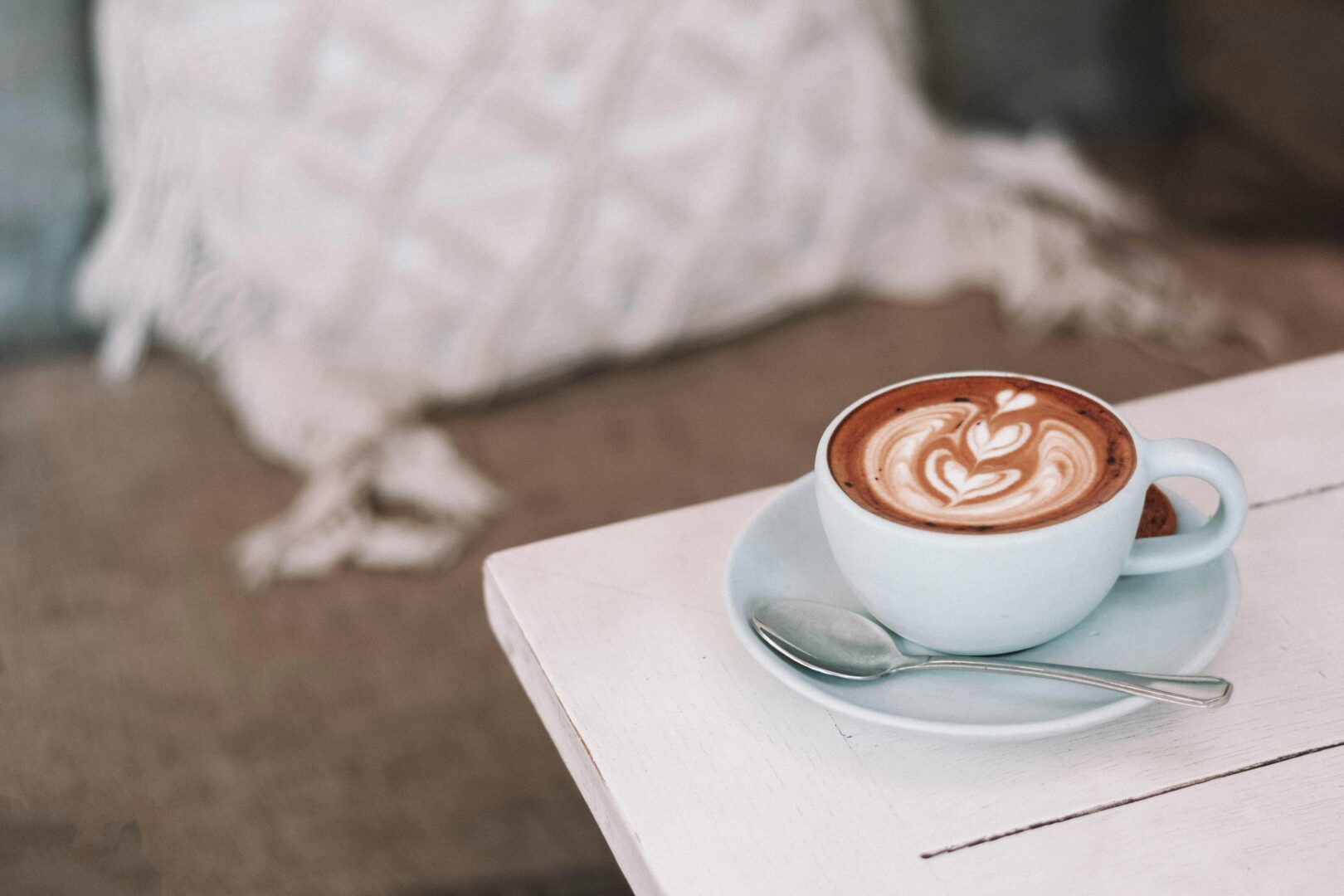 Latte with beautiful art in cozy café setting, perfect for morning relaxation.